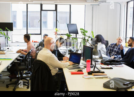 Computer programmers working in open plan office Stock Photo