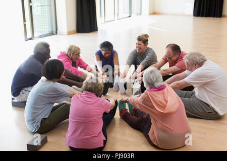 Active seniors exercising, stretching legs in circle Stock Photo