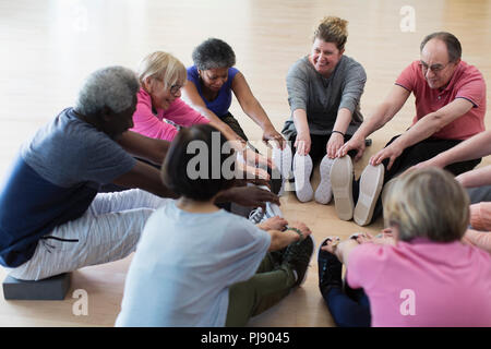 Smiling active seniors stretching legs in circle Stock Photo