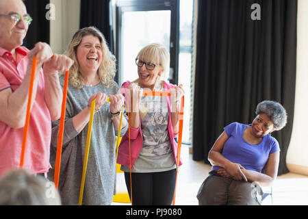 Happy instructor and active seniors exercising with straps Stock Photo