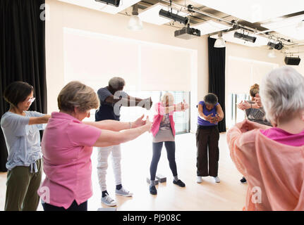 Active seniors exercising, stretching arms and back in circle Stock Photo
