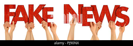 FAKE NEWS people holding up red wooden letters isolated on white background message newsletter misinformation propaganda concept Stock Photo