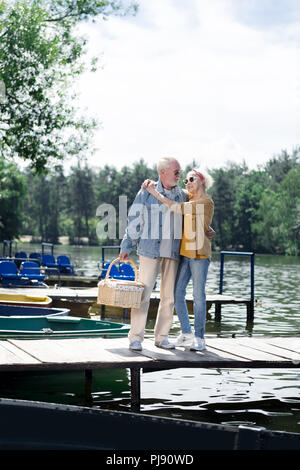 Aged wife and husband wearing sunglasses standing near the river Stock Photo