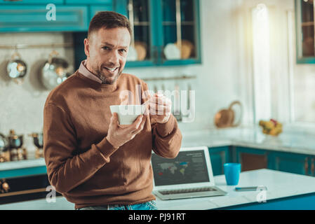 Attentive handsome man having breakfast in the kitchen Stock Photo
