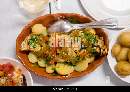 Traditional portuguese golden fish with red and green pepper served with cooked potatoes and tomato salad Stock Photo