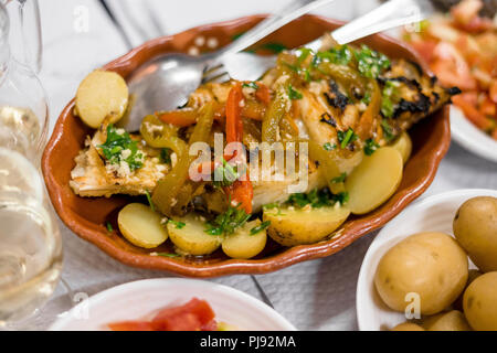 Traditional portuguese golden fish with red and green pepper served with cooked potatoes and tomato salad Stock Photo