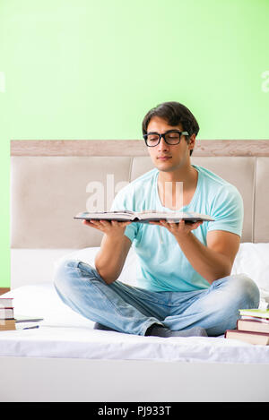 Student preparing for exams at home in bedroom sitting on the bed Stock Photo
