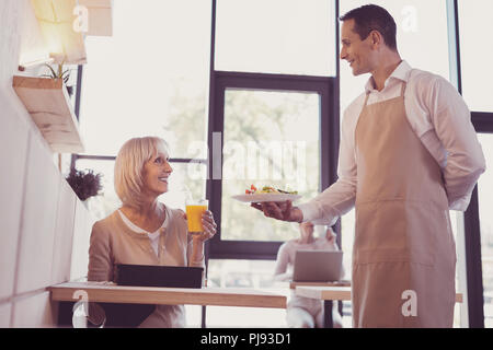 Pleasant senior woman sitting and drinking juice. Stock Photo