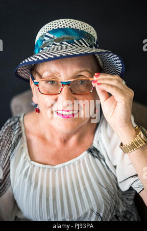 Elegant elderly woman sitting on the armchair with black background Stock Photo