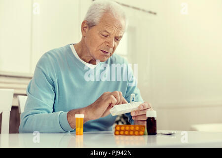 Depressed senior gentleman taking pills Stock Photo