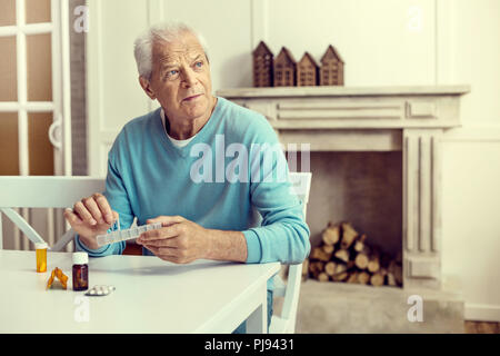 Worried man thinking of something while taking medication Stock Photo