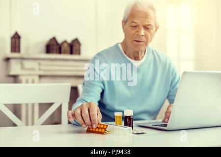 Elderly man reaching for his medication Stock Photo