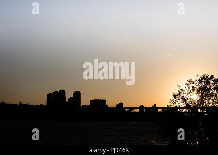 a silhouette of building and bridge across Han river in the sunset from riverside park, Seoul, Korea Stock Photo