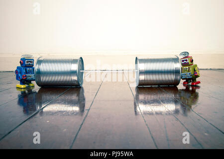 retro robots on tin can phones on a wooden floor with reflection Stock Photo