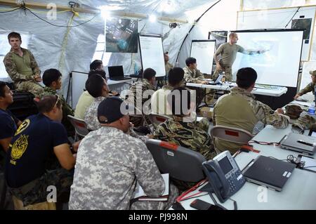 JOINT BASE PEARL HARBOR-HICKAM, Hawaii (July 02, 2018) - A Soldier from the U.S. Army's 1st Battalion, 1st Special Forces Group (ABN) conducts an intelligence brief as multinational SOF teams prepare for a raid during RIMPAC 2018. Twenty-five nations, more than 45 ships and submarines, about 200 aircraft, and 25,000 personnel are participating in RIMPAC from June 27 to Aug. 2 in and around the Hawaiian Islands and Southern California. The world's largest international maritime exercise, RIMPAC provides a unique training opportunity while fostering and sustaining cooperative relationships among Stock Photo