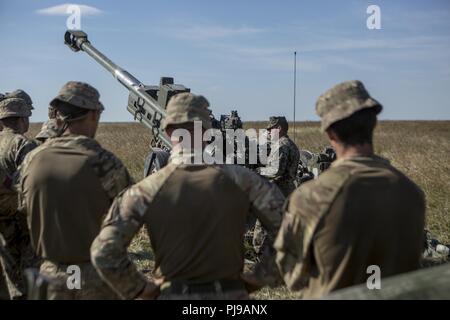 U.S. Marine Corps Staff Sgt. David Nunez, the battery gunnery sergeant of Echo Battery, 2nd Battalion, 10th Marine Regiment (2/10), 2nd Marine Division, explains proper firing procedures of the M777 Howitzer to British Soldiers assigned to 1st Royal Horse Artillery at Salisbury, England, July 3, 2018. Marines with the unit conducted live-fire exercises using the M777 Howitzer during exercise Green Cannon 18. Green Cannon is a multinational training exercise providing U.S. Marines the opportunity to exchange tactics and techniques as well as project lethality and combat power across the globe a Stock Photo