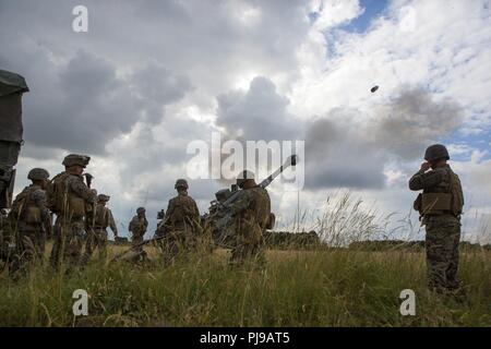 U.S. Marines with Echo Battery, 2nd Battalion, 10th Marine Regiment (2/10), 2nd Marine Division, fire an M777 Howitzer at Salisbury, England, July 5, 2018. Marines with the unit conducted live-fire exercises using the M777 Howitzer during exercise Green Cannon 18. Green Cannon is a multinational training exercise providing U.S. Marines the opportunity to exchange tactics and techniques as well as strengthen relationships among allied and partner nations. Stock Photo