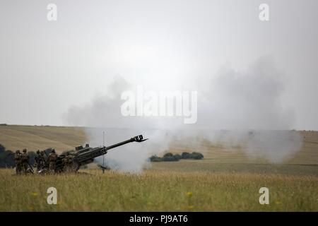 U.S. Marines with Echo Battery, 2nd Battalion, 10th Marine Regiment (2/10), 2nd Marine Division, fire a nM777 Howitzer at Salisbury, England, July 5, 2018 .Marines with the unit conducted live-fire exercises using the M777 Howitzer during exercise Green Cannon 18. Green Cannon is a multinational training exercise providing U.S. Marines the opportunity to exchange tactics and techniques as well as strengthen relationships among allied and partner nations. Stock Photo