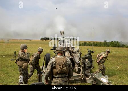 U.S. Marines with Echo Battery, 2nd Battalion, 10th Marine Regiment (2/10), 2nd Marine Division, fire an M777 Howitzer at Salisbury, England, July 5, 2018. Marines with the unit conducted live-fire exercises using the weapon system during exercise Green Cannon 18. Green Cannon is a multinational training exercise providing U.S. Marines the opportunity to exchange tactics and techniques as well as strengthen relationships among allied and partner nations. Stock Photo
