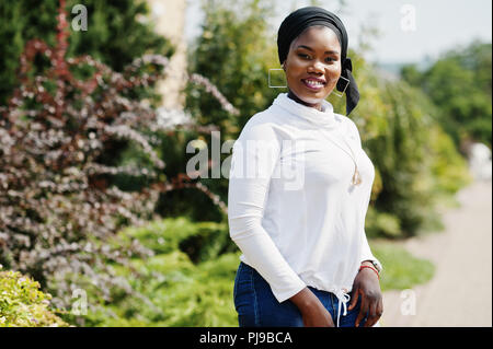 African muslim girl in black hijab, white sweatshirt and jeans posed outdoor. Stock Photo