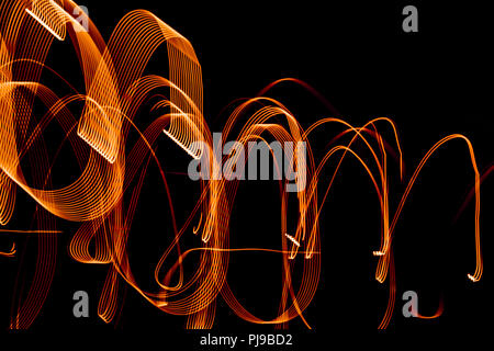Bright orange spiral patterns from light strips on a black background Stock Photo