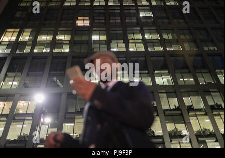 Businessman using smart phone below urban highrise at night Stock Photo