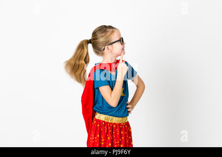 blond supergirl with glasses and red robe und blue shirt is posing in the studio Stock Photo