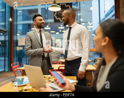 Businessmen handshaking, working in cafe Stock Photo