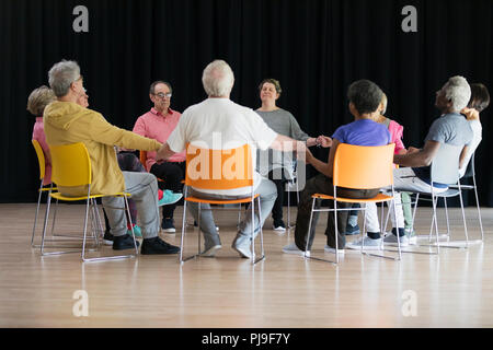 Active seniors meditating, holding hands in circle Stock Photo