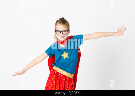 blond supergirl with glasses and red robe und blue shirt is posing in the studio Stock Photo