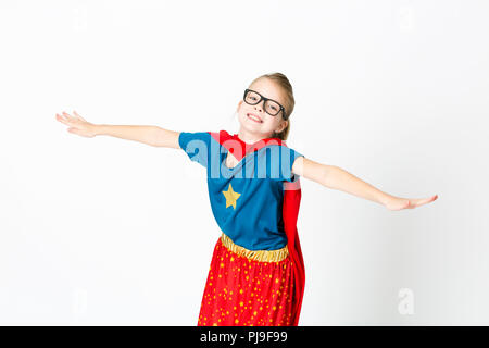 blond supergirl with glasses and red robe und blue shirt is posing in the studio Stock Photo