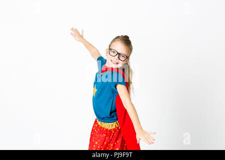 blond supergirl with glasses and red robe und blue shirt is posing in the studio Stock Photo