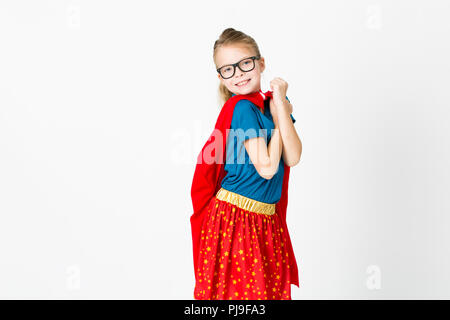 blond supergirl with glasses and red robe und blue shirt is posing in the studio Stock Photo