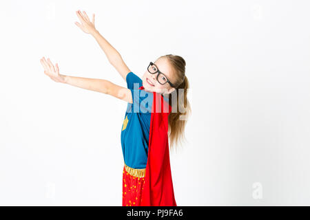 blond supergirl with glasses and red robe und blue shirt is posing in the studio Stock Photo