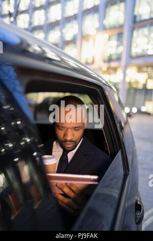 Businessman drinking coffee, using digital tablet in crowdsourced taxi Stock Photo
