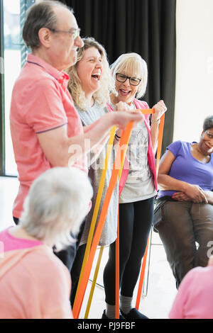 Smiling active seniors and instructor stretching, exercising with straps Stock Photo