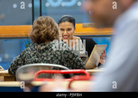 Businesswomen with digital tablet talking, working in cafe Stock Photo