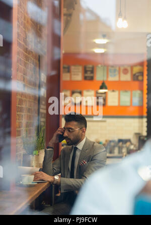 Businessman talking on smart phone, working in cafe Stock Photo