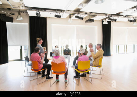Active seniors clapping for instructor in circle in community center Stock Photo