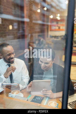 Smiling business people using digital tablet, working at cafe window Stock Photo
