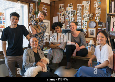 Portrait confident creative designers with dogs in office Stock Photo