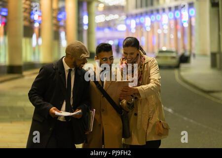 Business people using digital tablet on urban street at night Stock Photo