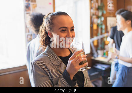 Portrait smiling businesswoman drinking tea in office Stock Photo