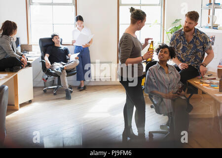 Creative business people drinking beer and talking in office Stock Photo