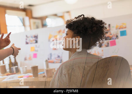 Creative female designer listening to colleague in office Stock Photo