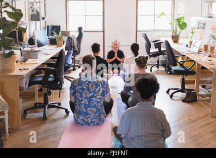 Creative business people meditating in office Stock Photo