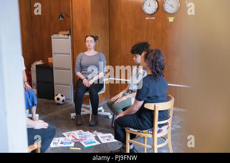 Serene, creative businesswomen meditating in circle, taking a break in meeting Stock Photo