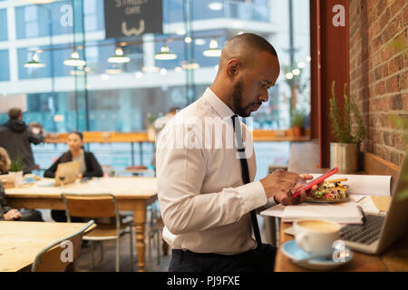 Businessman using smart phone and eating lunch in cafe Stock Photo