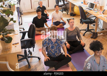 Serene creative business people meditating in office Stock Photo