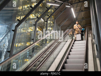 Businessman with suitcase on urban escalator Stock Photo